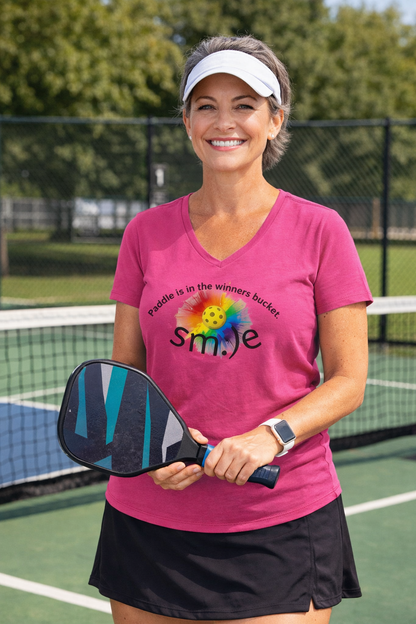 Woman on a pickleball court holding a paddle with a colorful design on her shirt.